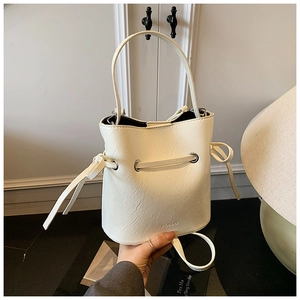 Close-up of cream bucket bag with drawstring closure and fine pebble grain texture