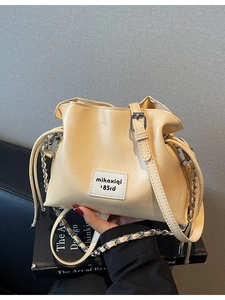 Creamy yellow drawstring bucket bag with metal chain strap and logo patch
