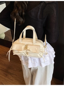 Sac bowling en cuir verni crème avec poches à nœuds et bandoulière amovible sur modèle