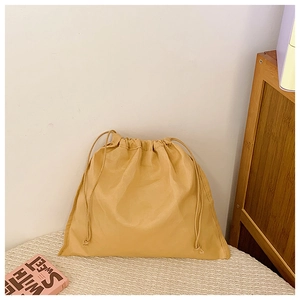 Détail d'une pochette jaune en cuir avec cordon de serrage et coutures précises pour sacs
