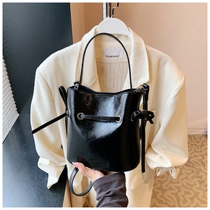 Close-up of black glossy bucket bag with crinkled patent leather and MUDUO logo