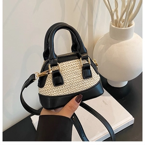 Detail der Mini-Muscheltasche mit beiger Webstruktur, schwarzem Leder und goldener Hardware