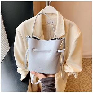 Close-up of light blue bucket bag with lychee grain texture and drawstring detail