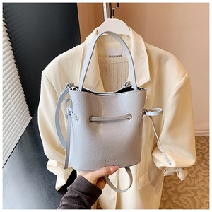 Close-up of light blue bucket bag with silver eyelets and adjustable strap in use