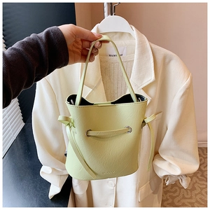 Close-up of light green leather bucket bag featuring drawstring and embossed logo detail