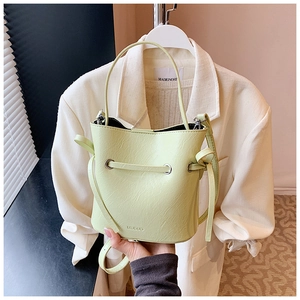 Detail of light green leather bucket bag with brand logo and drawstring closure