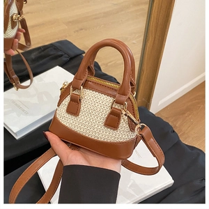 Detail der Mini-Muscheltasche mit cremefarbener Strohstruktur und braunem Lederbesatz