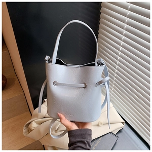 Detail view of light blue bucket bag showing soft pleated synthetic leather and MUQUO logo