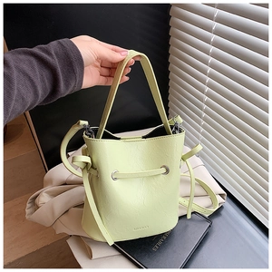 Detail of mint green faux leather bucket bag showing textured finish and drawstring closure