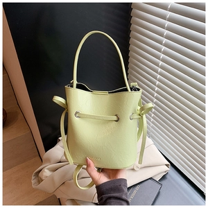 Close-up of lime green pebbled leather bucket bag with MUDUO logo and drawstring
