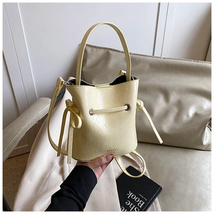 Detail showing creamy yellow bucket bag with drawstring closure and bow decoration