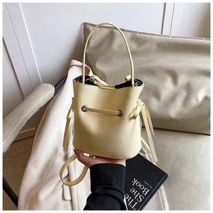 Detail of cream bucket bag showing smooth PU leather texture and drawstring closure