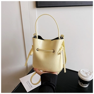 Detail of light yellow bucket bag with faux leather texture and adjustable shoulder strap