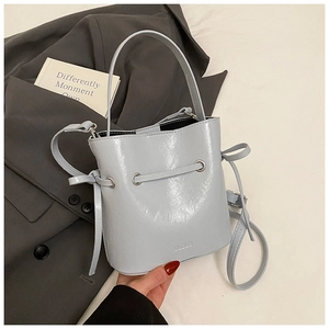 Close-up of light blue bucket bag with drawstring and handle on grey blazer