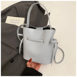 Close-up of light blue leather bucket bag with drawstring detail and adjustable strap