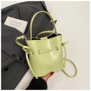 Detail of light green bucket bag showing glossy leather texture and drawstring closure