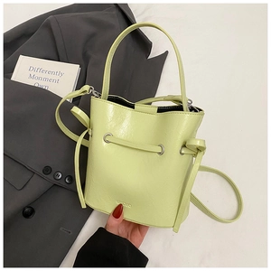 Detail of light green bucket bag showing MUDUO logo and adjustable shoulder strap