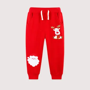 Detail of red cotton kids joggers featuring Santa Claus and reindeer embroidery patches