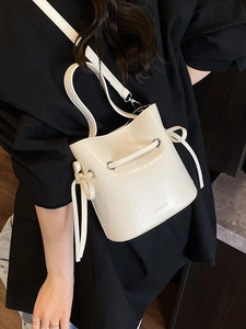 Chic cream white bucket bag with drawstring and silver hardware shown as a crossbody