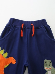 Navy blue knitted cotton toddler joggers featuring colorful dinosaur embroidery and orange drawstrings