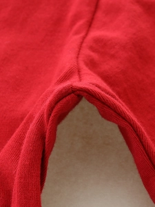 Detail of red long-sleeved girls' t-shirt featuring durable stitching and knitted texture