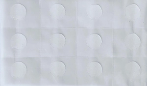 Macro shot of 12 round transparent pimple patches arranged on a matte backing sheet