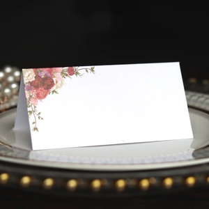 Macro detail of a folded wedding place card with elegant floral prints on a ceramic plate