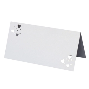 Detalle de tarjeta de mesa blanca plegada con calados de corazones y puntos láser