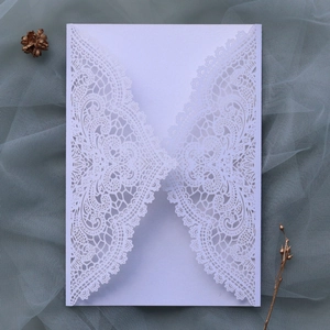Macro detail of white laser-cut lace wedding invitation envelope with floral patterns