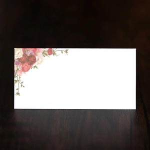 Detail of floral printed wedding place card with roses on white paper over wood