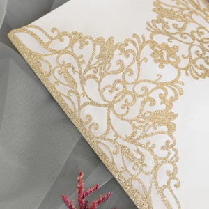 Détail de l'invitation de mariage découpée au laser avec paillettes dorées et fleurs