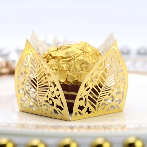 Detail of laser-cut gold pearlescent paper cupcake wrapper with elegant leaf patterns