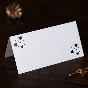 Detalle de tarjetas de mesa blancas con forma de corazón en una mesa de madera rústica