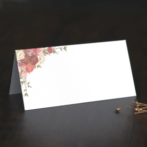 Detail of white place card with floral pattern on a textured dark wood background