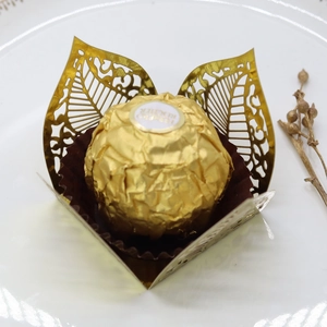 Macro detail of laser-cut gold leaf chocolate wrappers on a white plate