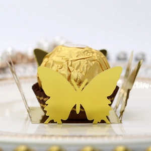 Macro detail of laser-cut butterfly chocolate holder in shiny gold for wedding decor