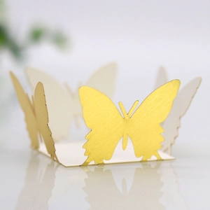 Macro detail of laser-cut champagne gold pearlescent butterfly paper cake wrappers
