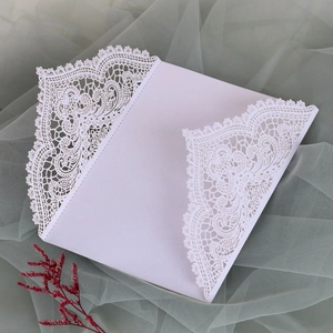 Makroaufnahme der weißen lasergeschnittenen Blumenspitze auf einer Hochzeitseinladung