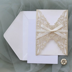 Détails de découpe laser sur invitation de mariage dorée pailletée avec ruban élégant