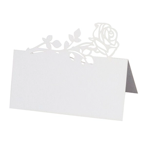 Macro shot of white laser-cut rose wedding place card with detailed hollow floral pattern
