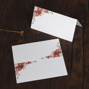 Detail of floral printed wedding place cards on dark wood table with dry flower decor