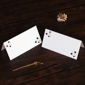 Detalle del patrón de corazón cortado por láser en tarjetas de mesa blancas de boda