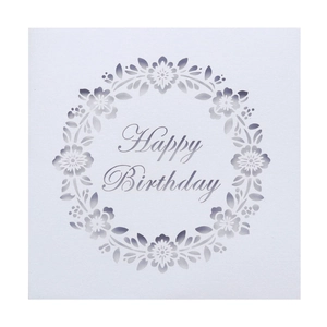 Macro detail of laser-cut floral pattern with Happy Birthday text on white cardstock