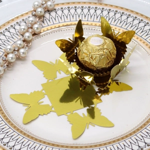 Detail of mirror gold butterfly favor box with laser cut hollow wings on a dessert plate