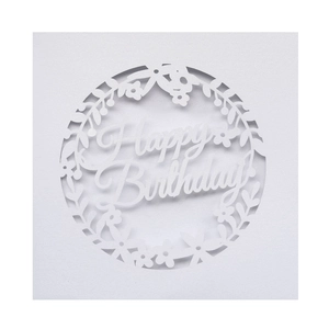 Detail of laser-cut white paper birthday card with elegant floral wreath and Happy Birthday text
