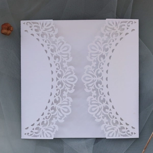 Detailed laser-cut pattern on white gatefold wedding invitation cover with floral motifs