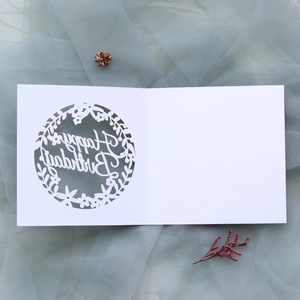 Close-up of white laser-cut floral birthday card with Happy Birthday greeting on mesh fabric