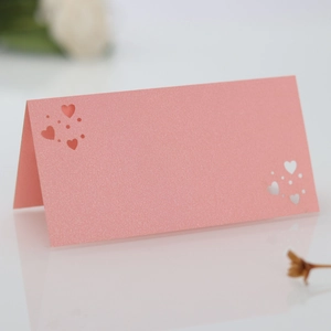 Detalle de tarjeta de mesa rosa brillante con corazón calado para bodas y eventos