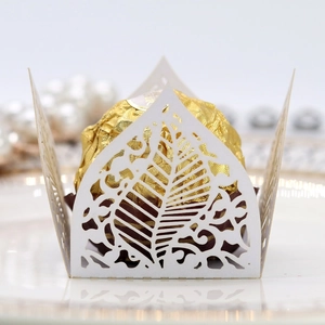 Macro detail of laser-cut hollow leaf chocolate wrapper with elegant pearl background