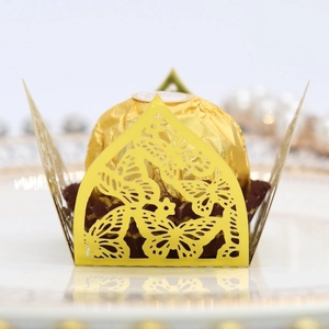 Close-up of laser-cut butterfly chocolate box with a golden candy on white plate